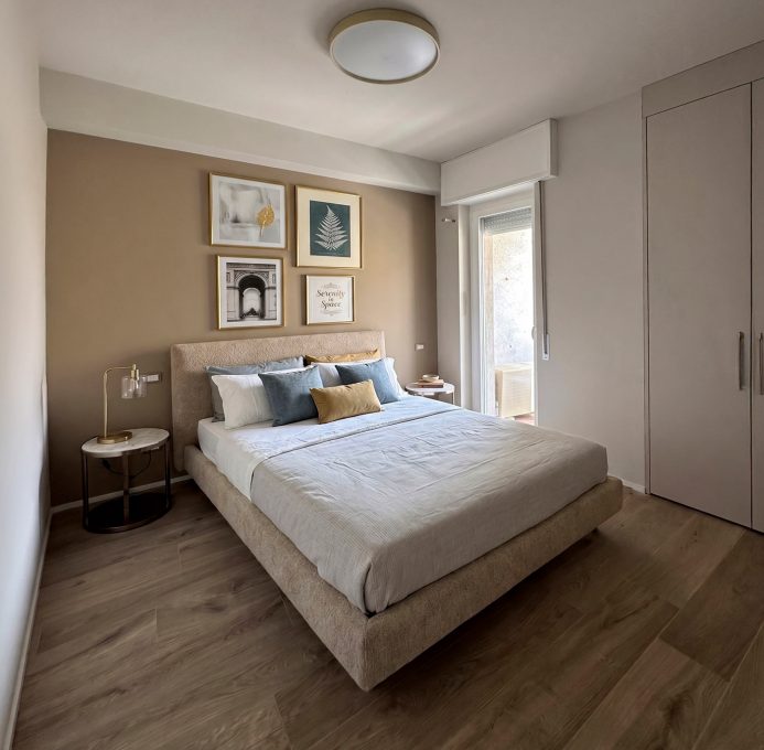 Camera da letto contemporanea con parete tortora e letto imbottito