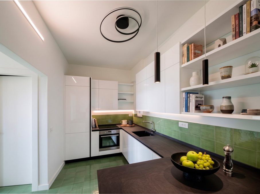 Cucina contemporanea ad angolo con finiture verde salvia e dettagli neri